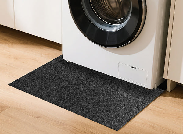 Accessory image for the WELKIN Garage Floor Mat (A1204) showing its use as a protective mat placed under a front-load washing machine to absorb spills and protect wooden flooring in a laundry area.