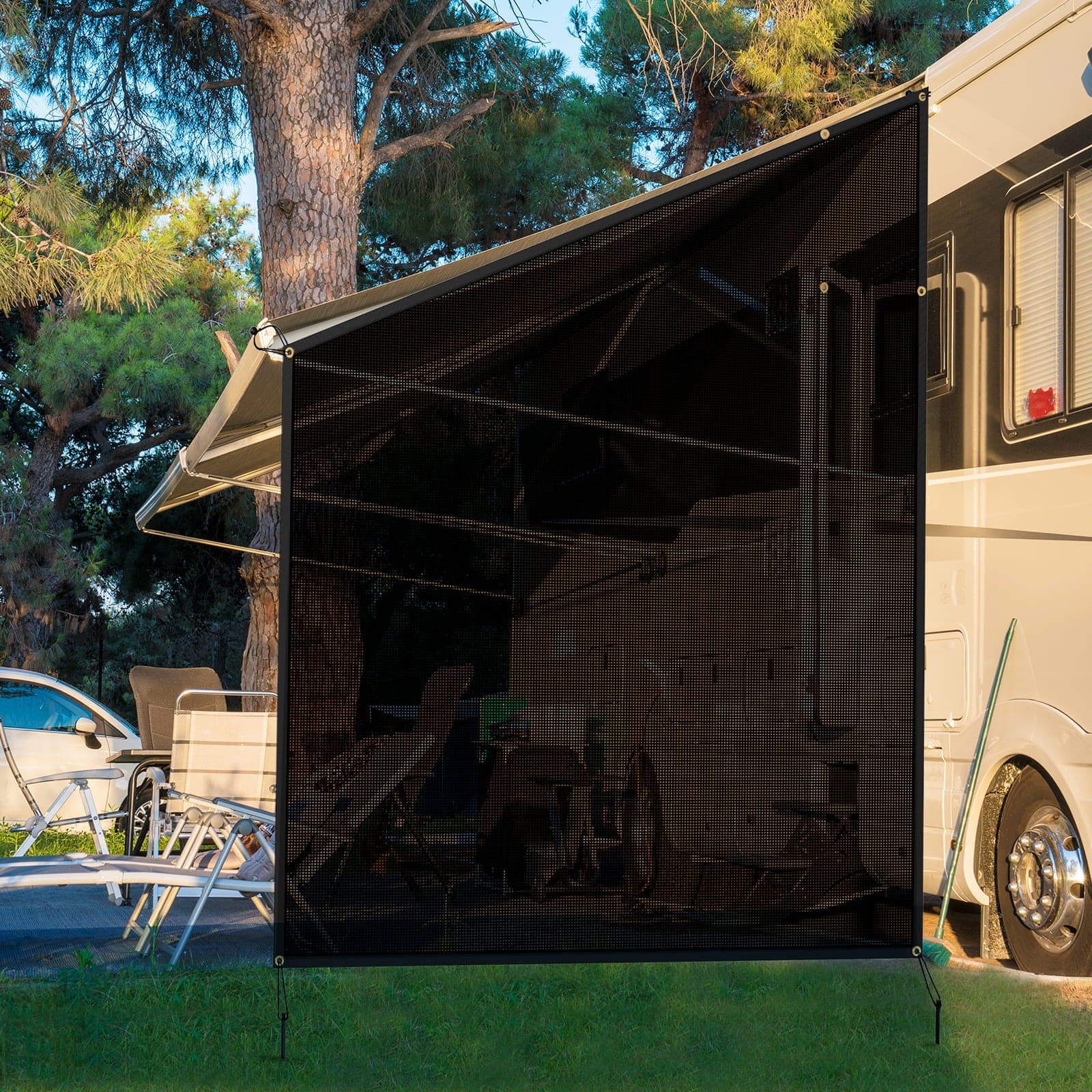 Outdoor use scene of the WELKIN Side RV Awning (A3201), showing the black mesh shade screen installed on the side of an RV to create a shaded and private campsite living area with chairs and a table.