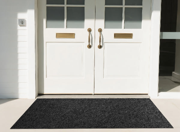 Accessory image for the WELKIN Garage Floor Mat (A1204) showing its use as a durable dark gray entryway mat placed in front of a white double door for dirt and moisture control.